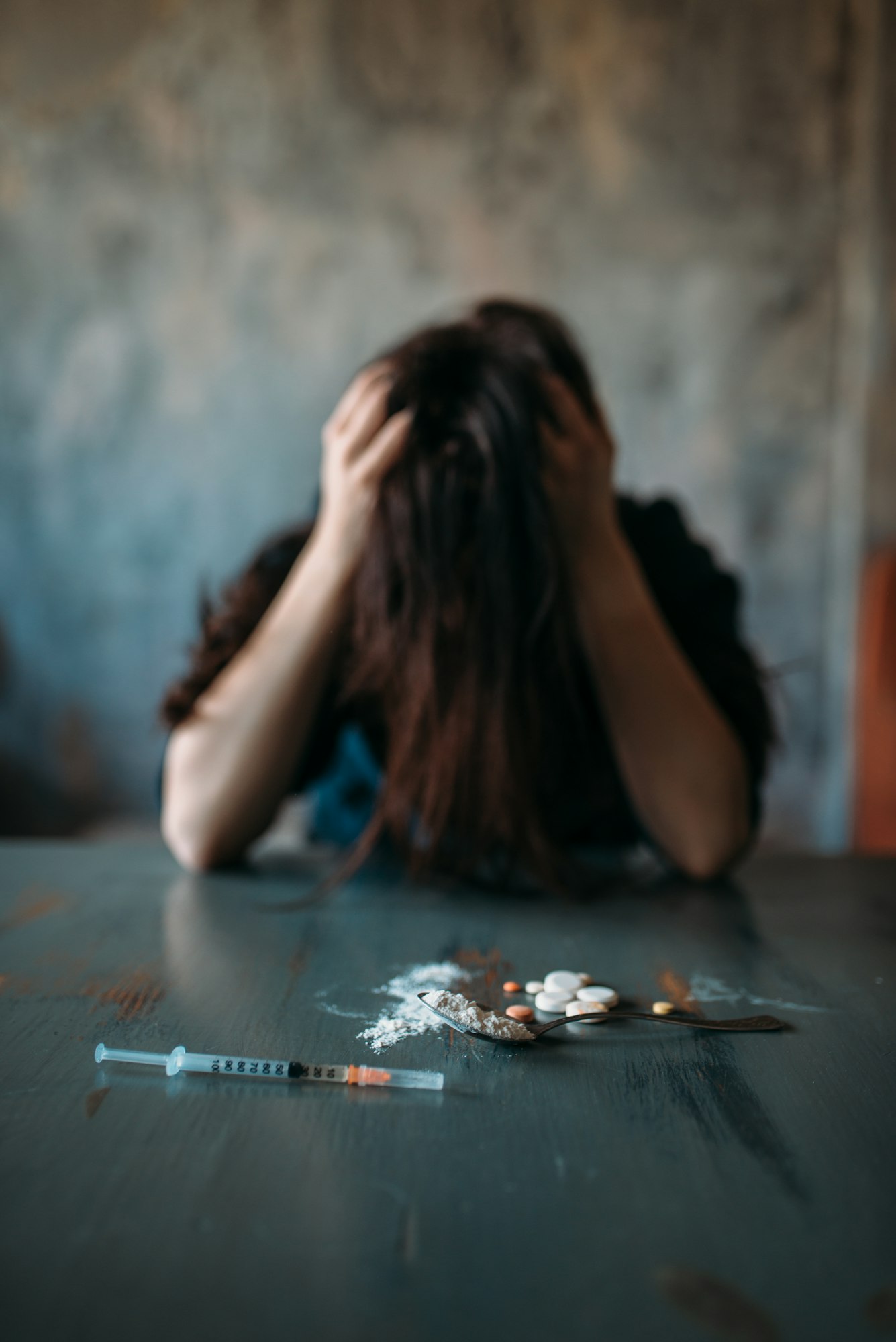 Junkie sitting at the table with drugs and syringe