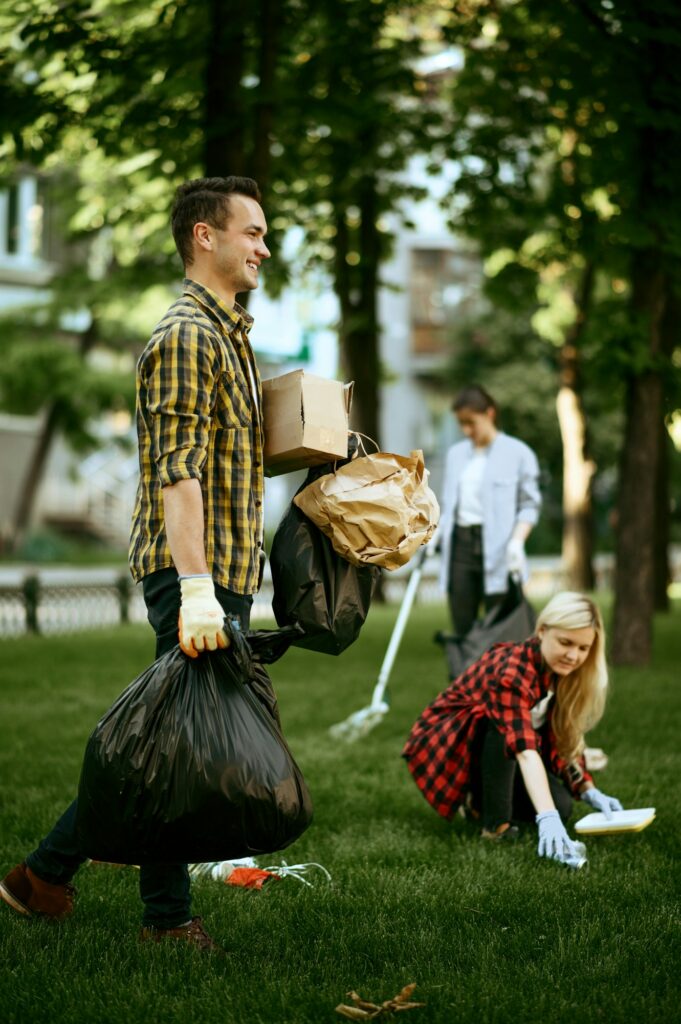 Man holds plastic trash bags in park, volunteering
